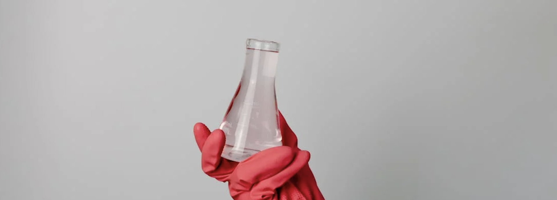 photograph of lab beaker being held by red glove